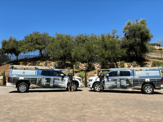 A Malibu garage door repair inspection by an Archway Garage Doors technician, featuring high-cycle blue torsion springs and a smart garage door opener system near a coastal home.