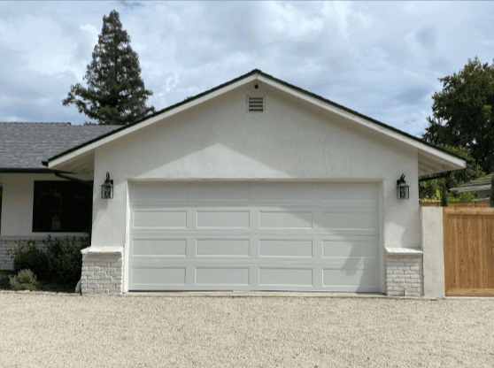 New garage doors and garage door openers are being installed at a Newhall home by an Archway Garage Doors technician, replacing a worn system with high-cycle blue torsion springs.
